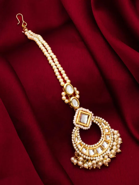 Regal maang tikka featuring pearls and intricate kundan work, exuding 'pearl majesty'.