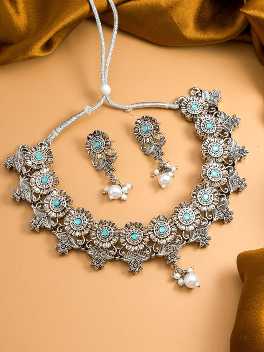 Oxidized silver necklace and earrings set with turquoise accents and a floral blossom design.